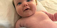 Grayson is registered to the contest to win money with this photo: baby, infant, blue_eyes, chubby_cheeks, smile, bare_chest, diaper, pillow, blanket, bed, knitted_fabric, curious, happy, indoor, close_up, skin, person, cute, portrait, resting