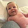 baby, infant, blue_eyes, chubby_cheeks, smile, bare_chest, diaper, pillow, blanket, bed, knitted_fabric, curious, happy, indoor, close_up, skin, person, cute, portrait, resting