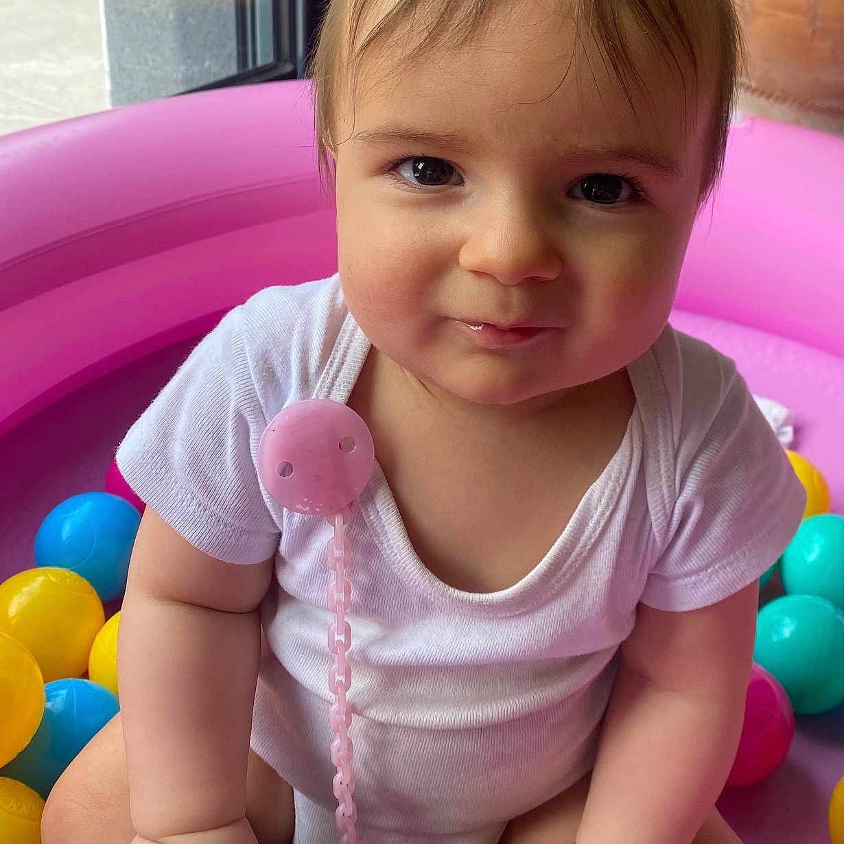 Noah participe au concours pour gagner de l'argent avec cette photo : baby, ball, blue_toy, child, chubby_cheeks, colorful, cute, face, hand, indoor, infant, natural_light, pink_pool, plastic_ball, playing, sitting, smile, toy, white_clothing, window