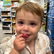 Lisandru participe au concours pour gagner de l'argent avec cette photo : aisle, baby, child, clothing, curious, cute, face, finger_in_mouth, fun, indoor, person, playful, retail, shopping_cart, short_hair, smiling, striped_shirt, supermarket, toddler, young_child