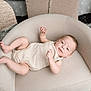 Tucker is registered to the contest to win money with this photo: baby, infant, armchair, beige, romper, disco_ball, balloon, celebration, smile, face, child, indoor, soft_furniture, cute, looking, happy, relaxing, decor, party, young
