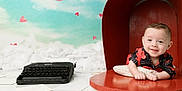 Tucker is registered to the contest to win money with this photo: baby, child, smiling, mailbox, typewriter, papers, red, blue_sky, hearts, airplane, prop, cute, portrait, indoor, playful, infant, background, photography, happy, pillow