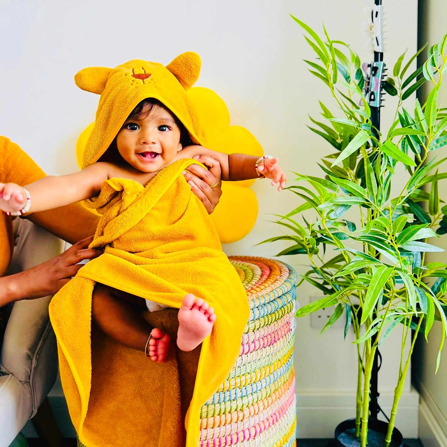 Prabhu joined the competition — help win amazing prizes! baby, child, colorful, cute, face, feet, furniture, hands, happy, hooded_towel, indoor, joyful, person, plant, potted_plant, room, smile, towel, woven_basket, yellow