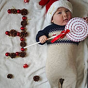 Zayn Youcef a rejoint le concours — aidez-le/la à gagner de superbes lots ! baby, blanket, celebration, child, christmas, cute, festive, holiday, holiday_decor, indoors, infant, lollipop, lying_down, onesie, pine_cones, portrait, red_ornaments, santa_hat, smiling, winter_clothing