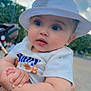 baby, child, hat, white_hat, tshirt, blue_jeans, outdoor, sky, clouds, hand, person, cute, portrait, holding, greenery, daylight, expression, infant, casual_clothing, closeup