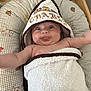 baby, towel, hood, tongue_out, cushion, animal_print, infant, cute, child, smiling, playful, arms_outstretched, blanket, soft, indoors, happy, portrait, closeup, skin, expression