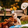 child, boy, calf, cow, animal, grass, farm, sunflowers, bench, hay_bale, cowboy_hat, outdoor, portrait, blue_eyes, denim, barefoot, cuddling, smile, bokeh, rural