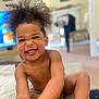 Karti is registered to the contest to win money with this photo: child, smiling, indoor, happy, hair, face, person, skin, arm, leg, living_room, furniture, blurred_background, home, couch, natural_light, playful, toddler, cute, expression