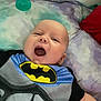 baby, infant, batman, smiling, lying_down, pillow, pacifier, bed, blanket, clothing, happy, cute, child, person, face, mouth_open, indoor, toddler, resting, young