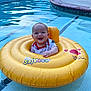 baby, child, pool, water, inflatable_ring, yellow, smiling, happy, floating, swimming_pool, summer, outdoor, cute, infant, splash, fun, playful, toddler, sunlight, recreation