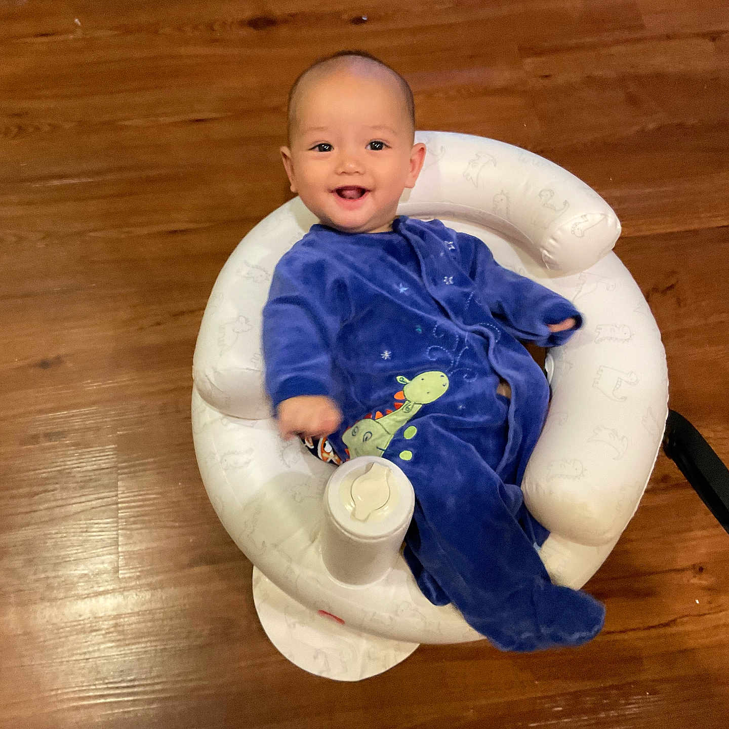 Kayden is registered to the contest to win money with this photo: baby, baby_furniture, blue_onesie, child, cozy, cushion, cute, dinosaur_print, flooring, happy, indoor, infant, infant_clothing, person, portrait, seated, smiling, white_baby_seat, wooden_floor, young_child