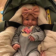 Margaux a rejoint le concours — aidez-le/la à gagner de superbes lots ! baby, infant, car_seat, pacifier, headband, bow, clothing, blanket, cozy, smile, cute, child, indoors, flooring, wood_floor, comfort, soft, toddler, person, seatbelt