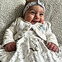 baby, infant, smile, headband, white_clothing, blanket, patterned_dress, cute, happy, portrait, child, indoors, soft_texture, animal_prints, small_hands, young_child, lying_down, cozy, adorable, head