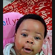 Kamsi is registered to the contest to win money with this photo: baby, child, face, portrait, indoor, striped_clothing, pink_cushion, red_blanket, curious_eyes, closeup, cute, infant, young_child, expression, cozy, soft_toys, person, skin, head, smiling