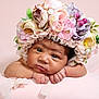 baby, child, flower_crown, hat, pink_background, resting, closeup, portrait, cute, infant, skin, hands, face, headwear, soft, colorful, floral, peaceful, indoors, newborn