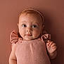 baby, infant, child, portrait, knitted_clothing, pink, headband, cute, expression, face, eyes, skin, hand, indoor, soft_lighting, warm_colors, newborn, person, studio, background