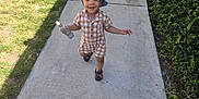 Miles joined the competition — help win amazing prizes! child, toddler, smiling, denim_hat, checkered_outfit, bottle, walking, sidewalk, concrete, grass, lawn, tree, shrub, greenery, shadow, shoes, sandals, outdoors, portrait, candid