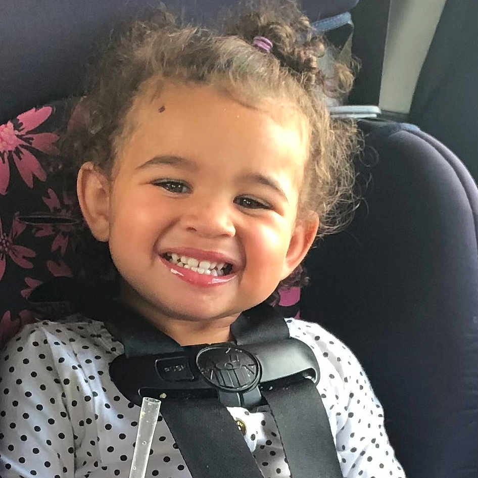 Aminah joined the competition — help win amazing prizes! baby, car_interior, car_seat, child, clothing, curly_hair, cute, face, hair_tie, happy, indoor, person, polka_dot_shirt, portrait, safety_harness, seat, seatbelt, smiling, toddler, young_child