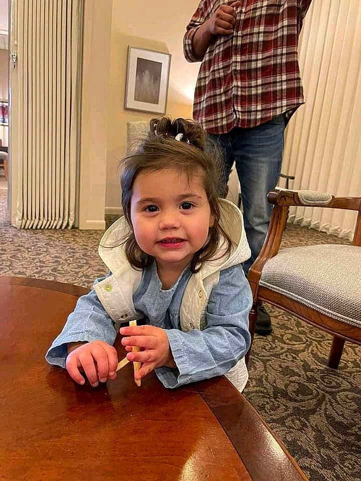 Renesmee is registered to the contest to win money with this photo: bag, belt, chair, child, eyewear, flooring, fun, happy, hardwood, joint, leisure, luggage_and_bags, person, plaid, room, sitting, standing, tartan, toddler, tree