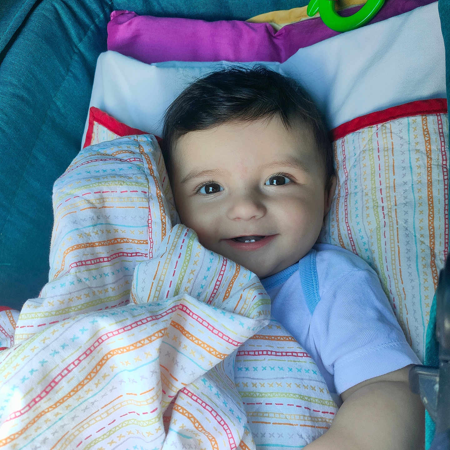 Dariy-Patrik a rejoint le concours — aidez-le/la à gagner de superbes lots ! baby, baby_carrier, blanket, child, closeup, clothing, comfort, cute, face, green_toy, hand, happy, indoors, infant, lying_down, patterned_blanket, portrait, smiling, toy, white_shirt