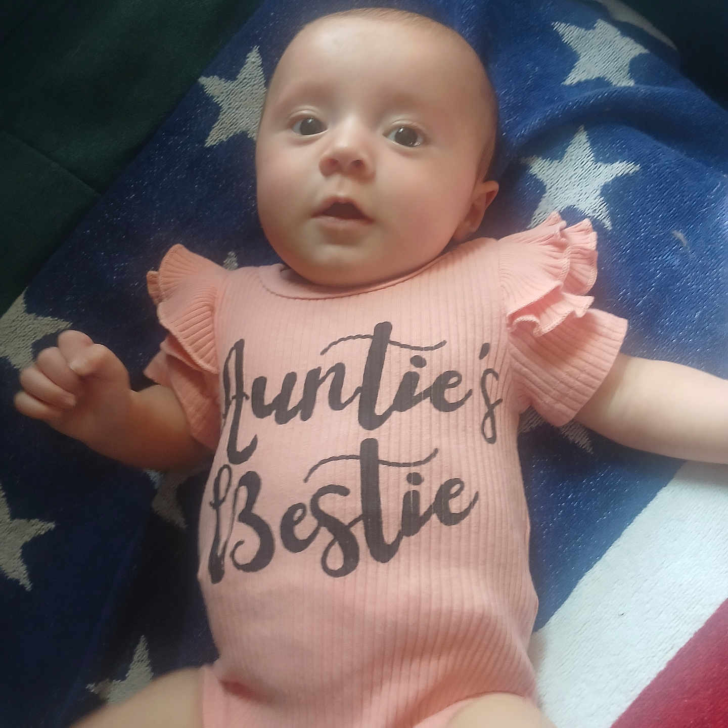Charletta joined the competition — help win amazing prizes! baby, infant, onesie, pink_clothing, blanket, stars, face, child, lying_down, indoor, cute, expression, hand, soft_light, portrait, toddler, skin, person, apparel, young