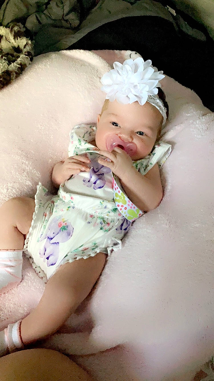 Kynleigh is registered to the contest to win money with this photo: baby, baby_toddler_clothing, child, embellishment, finger, flash_photography, hair_accessory, hand, happy, headband, headpiece, headwear, human_leg, jewellery, pattern, person, petal, pink, skin, textile