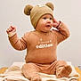 Eliott participe au concours pour gagner de l'argent avec cette photo : baby, child, infant, hat, bear_ears, brown_clothing, sitting, blanket, table, cute, smiling, indoor, portrait, warm_clothing, cozy, happy, person, face, headwear, limited_edition