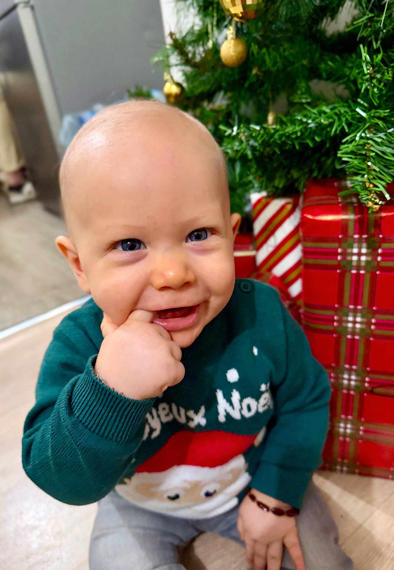 Eliott a rejoint le concours — aidez-le/la à gagner de superbes lots ! baby, child, smiling, blue_eyes, christmas_tree, christmas_presents, festive_sweater, holiday, indoor, floor, hand, face, cheerful, holiday_season, winter_clothing, sitting, cute, young_child, bracelet, holiday_decoration