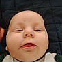 Hunter is registered to the contest to win money with this photo: baby, face, infant, child, lying_down, quilt, clothing, cheeks, mouth, skin, head, expression, eyes, sleepy, closeup, person, indoors, cute, young, apparel