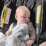 baby, car_seat, sleeping, stuffed_animal, blanket, child, infant, seatbelt, soft_toy, clothing, indoor, person, head, peaceful, rest, cute, hand, warning_label, fabric, transportation