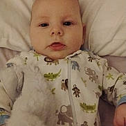 Hunter is registered to the contest to win money with this photo: baby, infant, pillow, onesie, animal_print, stuffed_toy, soft_toy, bed, sleepwear, child, cute, portrait, lying_down, hand, face, indoor, young_child, comfort, expression, zipped_clothing