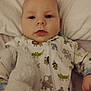 baby, infant, pillow, onesie, animal_print, stuffed_toy, soft_toy, bed, sleepwear, child, cute, portrait, lying_down, hand, face, indoor, young_child, comfort, expression, zipped_clothing