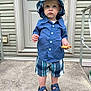 blue_shirt, boy, button_up_shirt, child, concrete, cookie, curious_expression, door, footwear, front_door, hat, outdoor, plaid_hat, plaid_shorts, porch, sandals, standing, summer_clothes, toddler, young_child