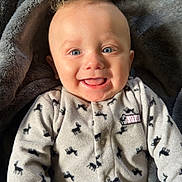 Sutton joined the competition — help win amazing prizes! baby, smiling, blue_eyes, curly_hair, onesie, deer_pattern, blanket, gray, soft_texture, happy, infant, cute, portrait, cozy, child, lying_down, indoors, warm, face, expression
