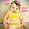baby, child, girl, yellow_dress, headband, pink_flower, sitting, portrait, cute, indoor, soft_background, curious_expression, skin, face, hands, bright_colors, text_overlay, name_text, date_text, closeup