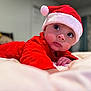 Ainnara joined the competition — help win amazing prizes! baby, infant, child, santa_hat, red_clothing, bed, blanket, indoors, portrait, cute, holiday, christmas, festive, soft_light, wide_eyes, face, hand, sleepwear, cozy, curious