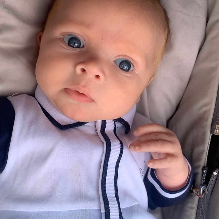 Ollie joined the competition — help win amazing prizes! apparel, baby, blue_eyes, child, closeup, clothing, curious, cushion, cute, fabric, face, hand, indoor, infant, navy, portrait, soft, striped, white, young_child