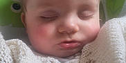 Charlie is registered to the contest to win money with this photo: baby, sleeping, blanket, knitted, cozy, face, rosy_cheeks, eyelashes, infant, cute, child, portrait, closeup, soft_lighting, indoor, resting, peaceful, white, clothing, background