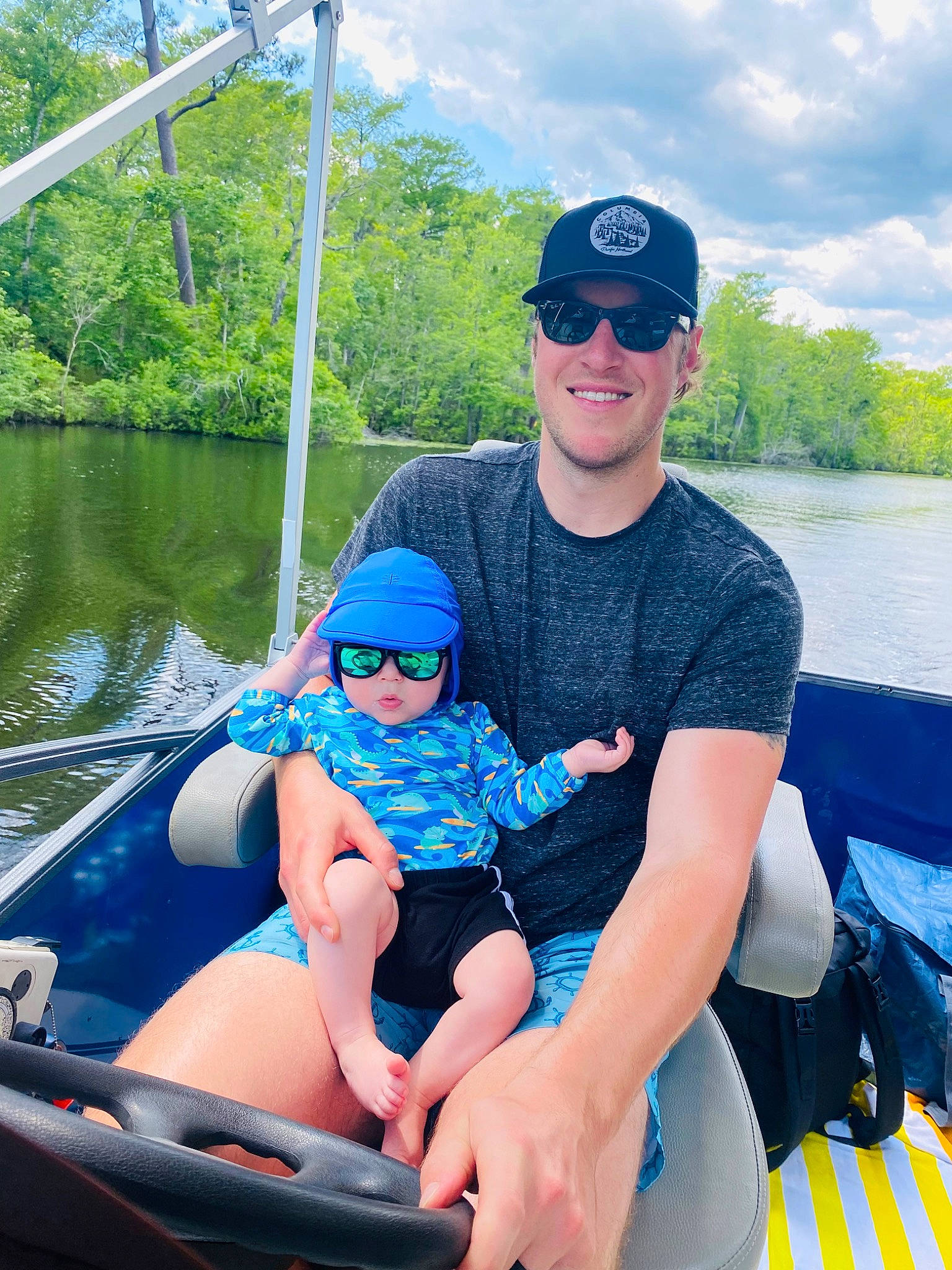 Hudson is registered to the contest to win money with this photo: boat, boats_and_boating_equipment_and_supplies, cloud, eyewear, fluvial_landforms_of_streams, fun, goggles, hat, headwear, joy, lake, leisure, muscle, outdoor_recreation, person, recreation, sky, smile, sunglasses, tree