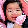 baby, infant, smile, pink_mitten, car_seat, child, dark_hair, cute, happy, face, close_up, indoor, seatbelt, apparel, young_child, head, skin, cheeks, expression, comfort