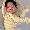 baby, child, blanket, onesie, yellow, duck_pattern, face, hair, smile, cute, infant, cozy, soft, bed, white, fabric, warm, portrait, sleepwear, toddler