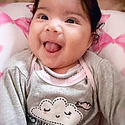 Amara Adame is registered to the contest to win money with this photo: baby, smiling, tongue_out, face, infant, clothing, grey_sweater, cute, happy, portrait, indoors, pink_background, cozy, child, person, soft_lighting, closeup, head, expression, dream_all_day