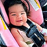 baby, car_seat, pink, smile, happy, child, seatbelt, mittens, infant, cute, face, clothing, hair, child_safety, car_interior, closeup, person, rosy_cheeks, comfort, portrait