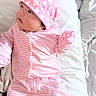 baby, infant, pink, hat, striped_clothing, heart_pattern, cute, lying_down, cushion, soft, sleepwear, child, newborn, portrait, indoors, apparel, person, face, cozy, resting