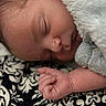 baby, blanket, close_up, closed_eyes, cozy, cuddled, face, fingers, fluffy, hair, hand, indoors, infant, newborn, patterned_fabric, peaceful, portrait, resting, skin, sleeping