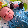 Exton is registered to the contest to win money with this photo: animal_print, baby, bed, bedding, blanket, blue_clothing, child, close_up, colorful, cozy, dumbbell, eyes, face, indoor, infant, looking_at_camera, lying_down, photograph, portrait, toy