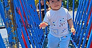 Mia joined the competition — help win amazing prizes! child, toddler, playground, blue_railings, hat, ear_hat, person, adult, outdoor, daylight, smile, walking, clothing, shoes, metal_platform, building, trees, sky, recreation, park