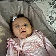 Louanna-Rose joined the competition — help win amazing prizes! baby, infant, pink_clothing, bow, face, pillow, bed, blanket, child, smiling, lying_down, cute, indoor, young_child, person, portrait, soft_toys, cozy, home, sleepwear