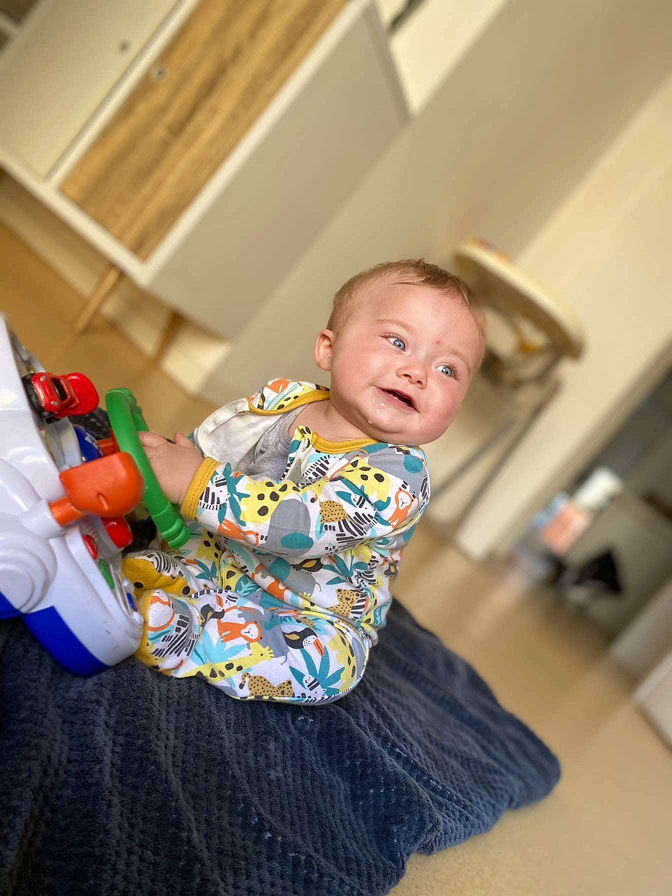 Kelyan a rejoint le concours — aidez-le/la à gagner de superbes lots ! baby, baby_toddler_clothing, child, comfort, floor, flooring, fun, happy, hardwood, leisure, pattern, person, room, sitting, sleeve, t_shirt, toddler, vacation, wood, wood_flooring