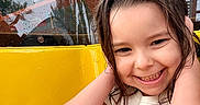 Emersyn is registered to the contest to win money with this photo: child, smiling, wet_hair, yellow, orange, outdoor, playground, raindrops, happy, person, tshirt, nature, trees, building, portrait, young, cute, fun, colorful, daylight